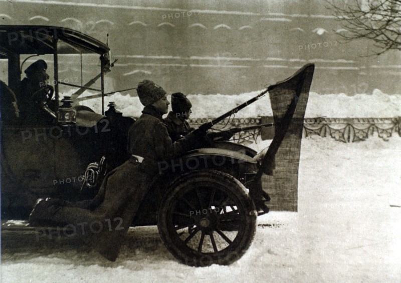 Russian Revolution of 1917. In Petrograd, soldiers riding on the running board of an automobile with red flags attached to their bayonets