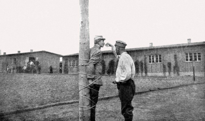 Première Guerre Mondiale. Au camp de Zwickau, un prisonnier français, lié au poteau, reçoit un verre d'eau d'un prisonnier roumain