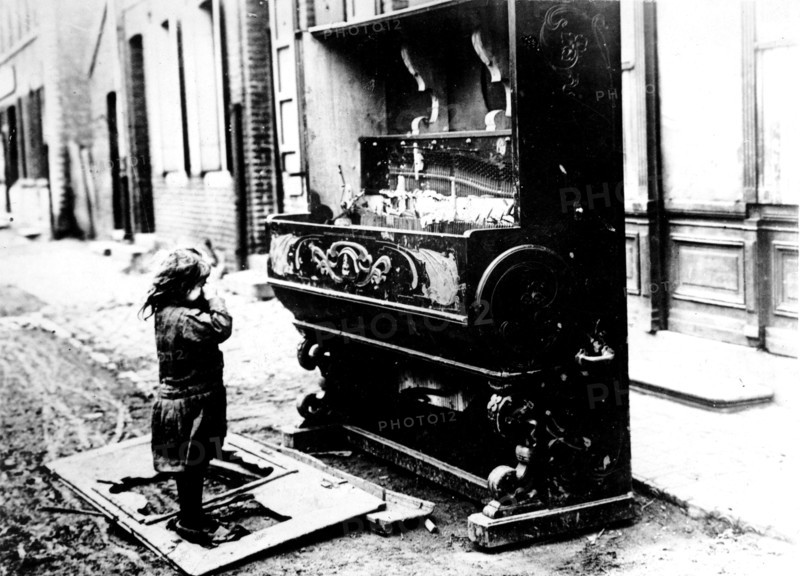 After the bombings, a child is crying before his destroyed piano