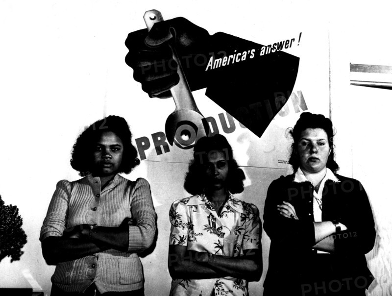 Photographie de Lee. Employées d'une fabrique de parachutes devant une affiche de propagande pour la production américaine