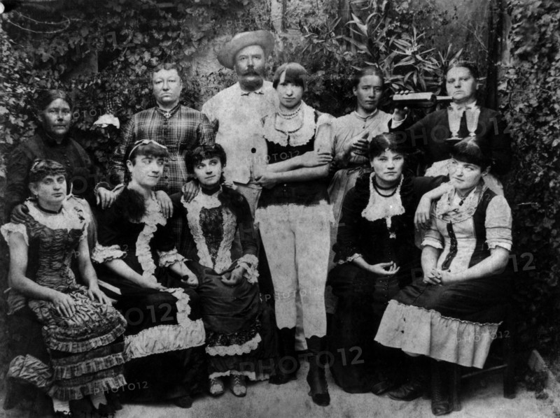 Boss of a brothel, surrounded by his ladies of pleasure