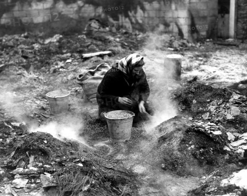 Belgian woman picking up cereals in a destroyed barn, 1944