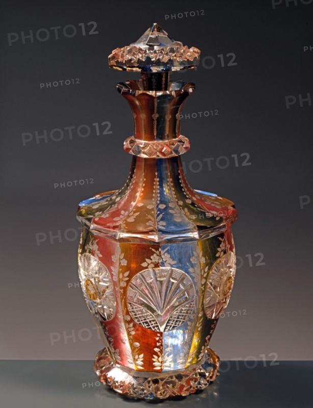 Bottle of Rosolio in Bohemian crystal of different colours, engraved with floral motifs.