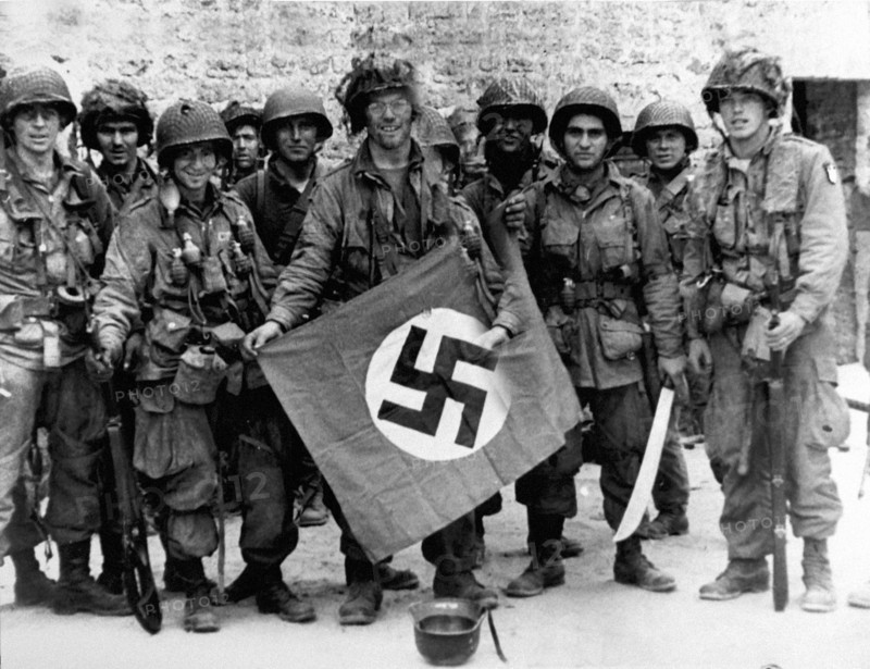US paratroopers pose with a captured Nazi flag, 1944