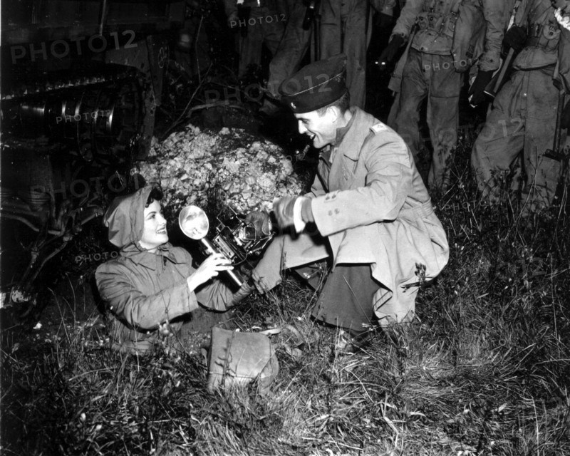 Un Major américain tend un appareil photo à une correspondante de guerre.
(Grande-Bretagne, 1943)