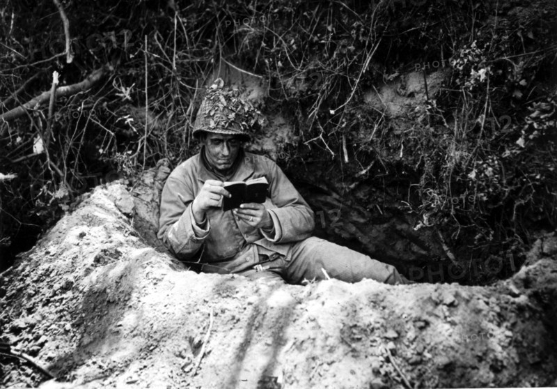 Soldat américain lisant un recueil de prières, dans la région de Saint-Lô.
(Juillet 1944)
