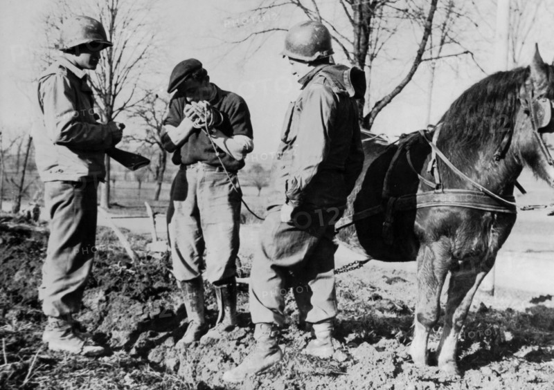 American troops discuss plowing with a French Farmer in Alsace, February 23, 1945