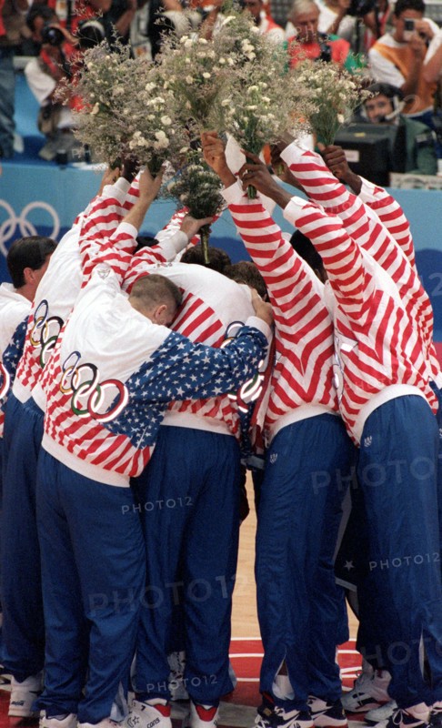Die Mitglieder des legendären US-amerikanischen " Dream Teams " bilden am 08.08.1992 bei den Olympischen Sommerspielen von Barcelona bei der Basketball-Siegerehrung vor lauter Freude ein schier unentwirrbares Knäuel und halten dabei aber die überreichten Blumensträuße sorgsam in die Höhe. Die Amerikaner haben das Spiel gegen Kroatien mit 117 : 85 klar für sich entschieden und sich die Goldmedaille geholt.