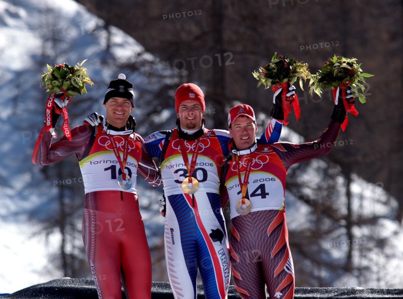 Der französische alpine Skifahrer Antoine Deneriaz (Mitte) gewinnt am 12.02.2006 die Goldmedaille bei der Abfahrt vor dem Österreicher Michael Walchhofer (l) und dem Schweizer Bruno Kernen (l) in Sestriere Borgata, Italien. Foto: Hiro Yakushi +++(c) Picture-Alliance / ASA+++