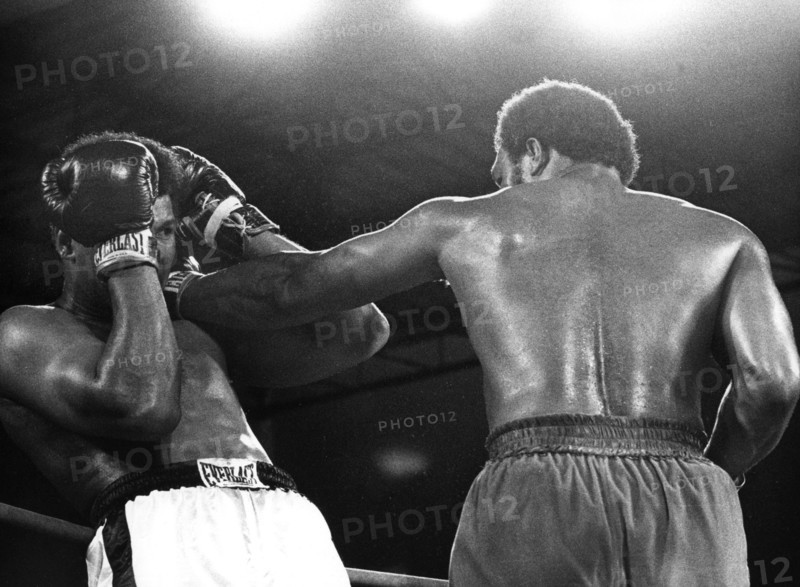 US-Schwergewichtsboxer Muhammad Ali (l) vermeidet in doppelter Deckung einen Kopftreffer seines Kontrahenten und Landsmanns George Foreman. Ali holt sich mit einem sensationellen K.o.-Sieg in der achten Runde gegen den sieben Jahre jüngeren Titelverteidiger am 30.10.1974 in Kinshasa (Zaire) den WM-Titel zurück. Damit ist der 32jährige der zweite Boxer, der den WM-Titel im Schwergewicht zurückerobert.