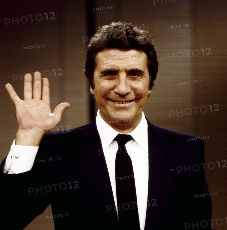 Gilbert BÉCAUD wintk in die Kamera