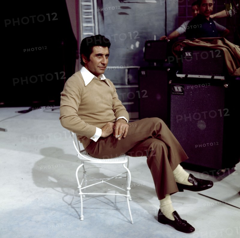Gilbert BÉCAUD sitzt auf einem Stuhl