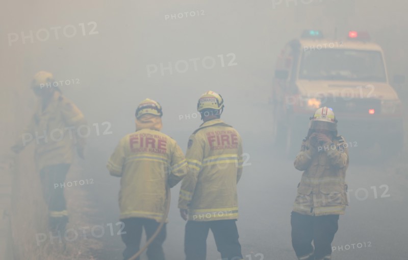 Firefighters take a break in smoke while battling bushfires near Taree, New South Wales, Australia, Nov. 11, 2019