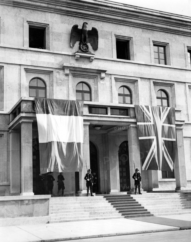 Die französische und die britische Fahne schmücken das Portal des "Führerhauses" am Königsplatz, in dem die Münchner Konferenz stattfindet. Auf dem Treffen zwischen Neville Chamberlain, Edouard Daladier, Benito Mussolini und Adolf Hitler soll versucht werden, den drohenden Krieg des Deutschen Reiches gegen die Tschechoslowakei abzuwenden. Im Münchner Abkommen wird die Abtretung des Sudetenlandes an Deutschland festgelegt.