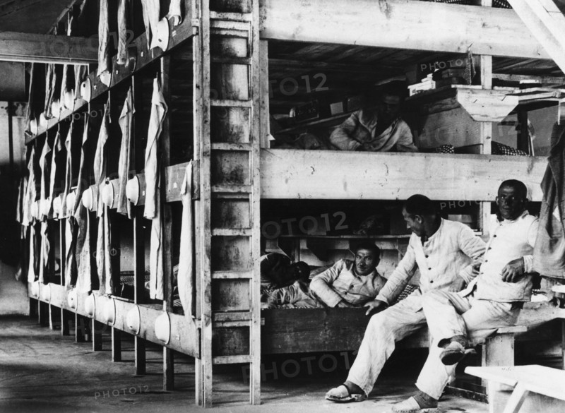 Häftlinge auf ihren Pritschen in einer Baracke des KZ Dachau. Um den zahlreichen Berichten in der ausländischen Presse über die Konzentrationslager entgegenzutreten, fand 1933 eine Pressebesichtigung in Dachau statt, um den geladenen Journalisten ein "sauberes" Konzentrationslager vorzuführen. Dieses Bild ist bei diesem Anlaß entstanden und zeigt eine geschönte Wirklichkeit. (Aufnahmedatum: 01.01.1933-31.12.1933)