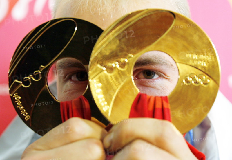(dpa) - German Andre Lange looks through his two gold medals at the Olympic bobsleigh and toboggan run in Cesana Pariol, Italy, 25 February 2006. Lange won gold in the two-man as well as in the four-man bobsleigh. Photo: Arne Dedert
