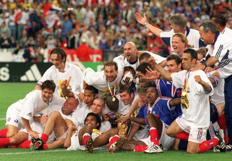 The players of the French national soccer team and their captin Didier Deschamps (C, turned away) and French goalgetter and midfielder Zinedine Zidane (C, behind World Cup) group together for a photograph and cheer with the World Cup trophy in front of them during the 1998 Soccer World Cup in Paris, France, 12 July 1998. France wins the game 3-0 against titleholder Brazil and wins the world champion title for the first time.