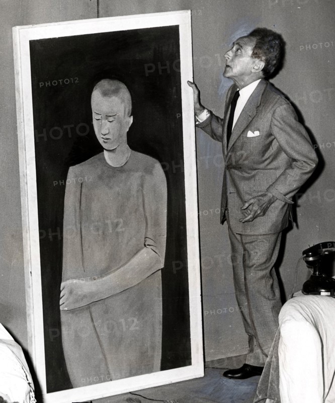 Cocteau hanging a painting at his place, 1958