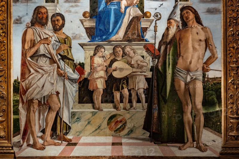 “Enthroned Madonna with infant Jesus  among Saints John the Baptist, Bartholomew, Agustine, Sebastian and three angels playing music”, by Bartolomeo Montagna