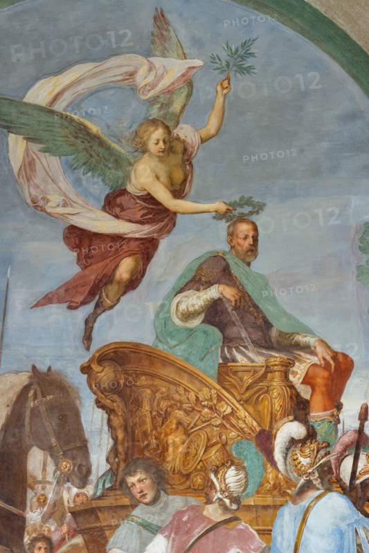 Medici Villa La Petraia, courtyard: “Triumphal entry of Cosimo I into Siena”, fresco from the cycle of the Fasti Medicei by Volterrano (Baldassarre Franceschini), 1636-1647.
In 1555 Cosimo I de' Medici conquered Siena with the help of the Imperials, a military feat which later earned him the title of Grand Duke, therefore a crucial moment for the Medici house. The fresco, with clear celebratory intentions, shows Cosimo making his triumphal entry into the city gates on a golden chariot, followed by a large group of dignitaries, welcomed by the Sienese senators and some citizens. 
Detail of a winged Victory who  crowns Cosimo I with a laurel wreath.
Villa medicea La Petraia, Firenze (FI) - Florence, Toscana - Tuscany, Italia - Italy