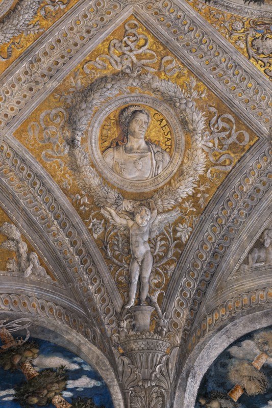 Ducal Palace: vault of the “Bridal Chamber or Camera Picta", which is a room located in the north-east tower of the Castle of San Giorgio in Mantua. It is famous for the cycle of frescoes that covers its walls, a masterpiece by Andrea Mantegna, created between 1465 and 1474.
Detail of the vault: lozenge with a golden background that encloses a circular garland which in turn encloses the portrait of the Roman emperor “Julius Caesar”. The garland is supported by a putto.
Palazzo Ducale, Mantova (MN) - Mantua, Lombardia - Lombardy, Italia - Italy