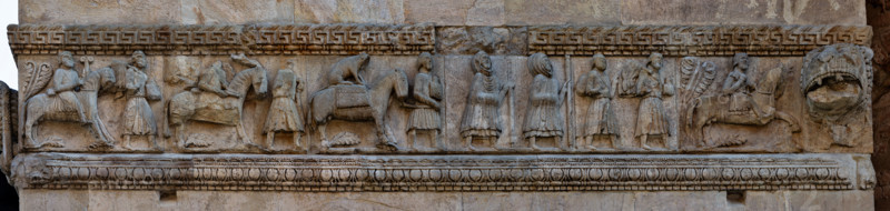 Fidenza, duomo (Cattedrale di San Donnino), torre di destra (Torre del Trabucco), fianco meridionale: fregio composto da sei formelle con “Il Corteo di Carlo Magno di ritorno in Francia dopo aver liberato Roma dai Saraceni”. Tale interpretazione è avvalorata dalla formella che raffigura un cavaliere che tiene alla briglia un cavallo con in groppa il ghepardo che l'imperatore impiegava nella caccia. 
È stato interpretato in passato come la raffigurazione di pellegrini sulla strada per Roma (al punto da diventare una delle icone simbolo della via Francigena). 

[ENG]
Fidenza, Duomo (Cathedral of San Donnino), right tower (Trabucco Tower), southern side: frieze composed of six panels with “The Procession of Charlemagne returning to France after having freed Rome from the Saracens”. This interpretation is supported by the panel depicting a knight holding the bridle of a horse with a cheetah on its back that the emperor used for hunting.
It has been interpreted in the past as the depic...