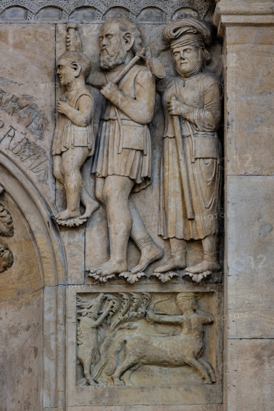Fidenza, duomo (Cattedrale di San Donnino), facciata, formella: un centauro colpisce un cervo  e sopra una famiglia di pellegrini poveri verso la Via Francigena
Opera di Benedetto Antelami.

[ENG]
Fidenza, cathedral (Cathedral of San Donnino), facade, panel: a centaur strikes a deer and above a family of poor pilgrims towards the Via Francigena
Work by Benedetto Antelami.
Cattedrale di S. Donnino, Fidenza (PR), Emilia Romagna, Italia - Italy