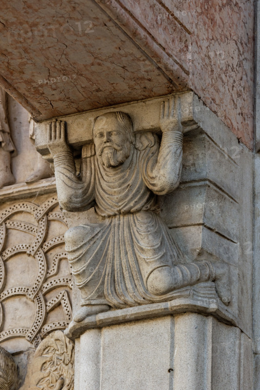 Fidenza, Duomo (Cattedrale di San Donnino), facciata, il portale maggiore,  protiro: telamone di sinistra.
Opera di Benedetto Antelami e bottega.

[ENG]
Fidenza, Duomo (St. Donnino Cathedral), the façade, the main portal, the prothyrum: the left telamon.
Work by Benedetto Antelami  and workshop.
Cattedrale di San Donnino, Fidenza (PR), Emilia-Romagna, Italia - Italy