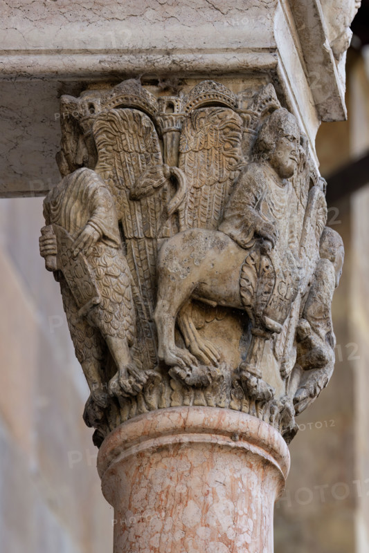 Fidenza, Duomo (Cattedrale di San Donnino), facciata, portale maggiore, protiro: il capitello di destra con “i Quattro Evangelisti”.  A A sinistra “S. Giovanni”, con piedi d’aquila e l’iscrizione: IN / PRI / N.CI / PIO (In principio (Gv 1, ) = in principio…). A destra “S. Matteo” con piedi umani che porta l’iscrizione: LIBER. / [G]ENE / [R]ACI / [ON]NIS. (Liber generationis (Mt 1,1)= Libro della generazione…); 
Opera di Benedetto Antelami e bottega.

[ENG]
Fidenza, Duomo (Cathedral of San Donnino), facade, main portal, prothyrum:  the right capital with “the Four Evangelists”. On the left "St. John", with eagle's feet and the inscription: IN / PRI / N.CI / PIO (In the beginning (Jn 1, ) = in the beginning…). On the right “St. Matthew” with human feet bearing the inscription: LIBER. / [G]ENE / [R]ACI / [ON]NIS. (Liber generationis (Mt 1,1) = Book of the generation…);
Work by Benedetto Antelami and workshop.
Cattedrale di San Donnino, Fidenza (PR), Emilia-Romagna, Italia - Italy