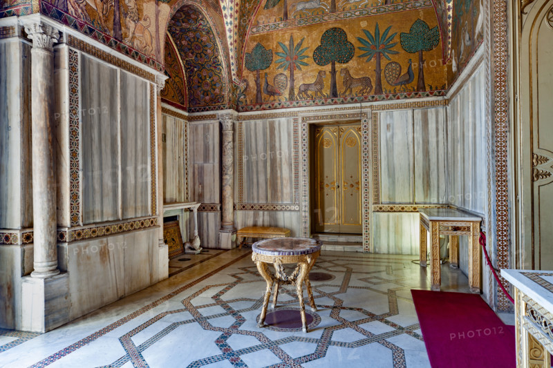 Palermo, Palazzo Reale o Palazzo dei Normanni, Torre Pisana, Sala di Re Ruggero: veduta della sala voluta da Re Ruggero II d'Altavilla. E' caratterizzata da ampie superfici a mosaico di grande pregio raffiguranti elementi vegetali (palme e banani) e scene di carattere aulico e venatorio, simboli del potere normanno (battute di caccia con arcieri e cervi, rappresentati pavoni, cigni, oltre i mitologici centauri, grifi e altri animali esotici tra cui leopardi e tigri fra lussureggiante vegetazione). I mosaici sono di stile greco - bizantino (secolo XIII).

[ENG]
Palermo, The Royal Palace or Palazzo dei Normanni (Palace of the Normans), Pisana Tower,  the King Roger Room: view of the Room which was commissioned by King Roger II d'Altavilla. It is characterized by large mosaic surfaces of great value representing plant elements (palms and banana trees) and scenes of courtly and hunting style, symbols of the Norman power (hunting scenes with archers and deer, peacocks, swans, and mytholo...