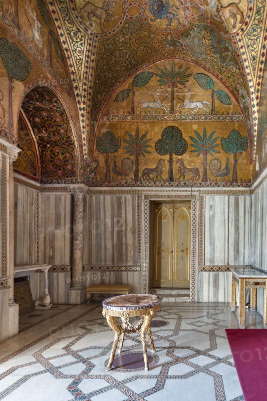 Palermo, Palazzo Reale o Palazzo dei Normanni, Torre Pisana, Sala di Re Ruggero: veduta della sala voluta da Re Ruggero II d'Altavilla. E' caratterizzata da ampie superfici a mosaico di grande pregio raffiguranti elementi vegetali (palme e banani) e scene di carattere aulico e venatorio, simboli del potere normanno (battute di caccia con arcieri e cervi, rappresentati pavoni, cigni, oltre i mitologici centauri, grifi e altri animali esotici tra cui leopardi e tigri fra lussureggiante vegetazione). I mosaici sono di stile greco - bizantino (secolo XIII).

[ENG]
Palermo, The Royal Palace or Palazzo dei Normanni (Palace of the Normans), Pisana Tower,  the King Roger Room: view of the Room which was commissioned by King Roger II d'Altavilla. It is characterized by large mosaic surfaces of great value representing plant elements (palms and banana trees) and scenes of courtly and hunting style, symbols of the Norman power (hunting scenes with archers and deer, peacocks, swans, and mytholo...
