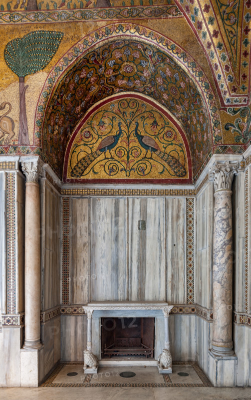 Palermo, The Royal Palace or Palazzo dei Normanni (Palace of the Normans), Pisana Tower, the King Roger Room: view of the Room which was commissioned by King Roger II d'Altavilla. It is characterized by large mosaic surfaces of great value representing plant elements (palms and banana trees) and scenes of courtly and hunting style, symbols of the Norman power (hunting scenes with archers and deer, peacocks, swans, and mythological centaurs, griffins and other exotic animals including leopards and tigers among luxuriant vegetation). Mosaics are characterised by Greek Byzantiene style (XIII century).
Detail of a niche with fireplace with two lion sculptures supporting the shelf; a lunette with a mosaic representing peacocks; rich marble coverings and angular columns.
Palazzo Reale (Palazzo dei Norma, Palermo (PA), Sicilia - Sicily, Italia - Italy