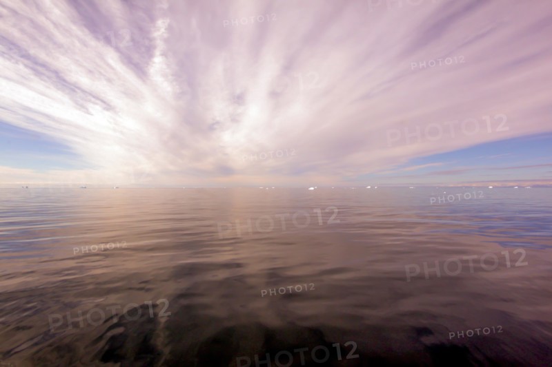 Sun rays through clouds above the ocean, Greenland