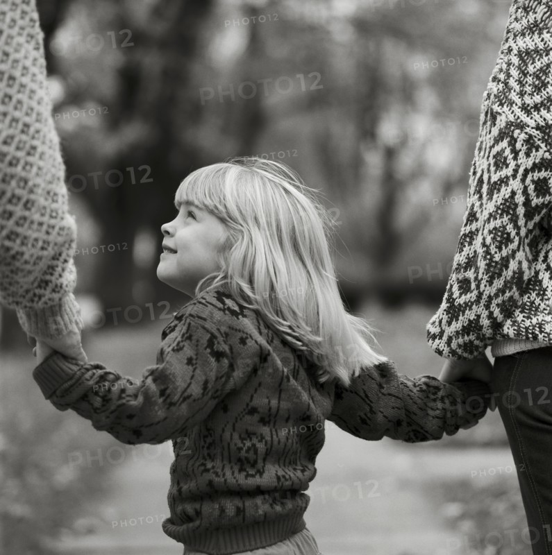Young Blonde Girl Holding Parents' Hands