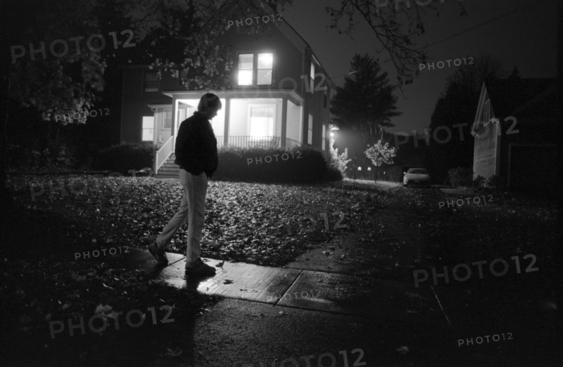 Man Walking Past House at Night