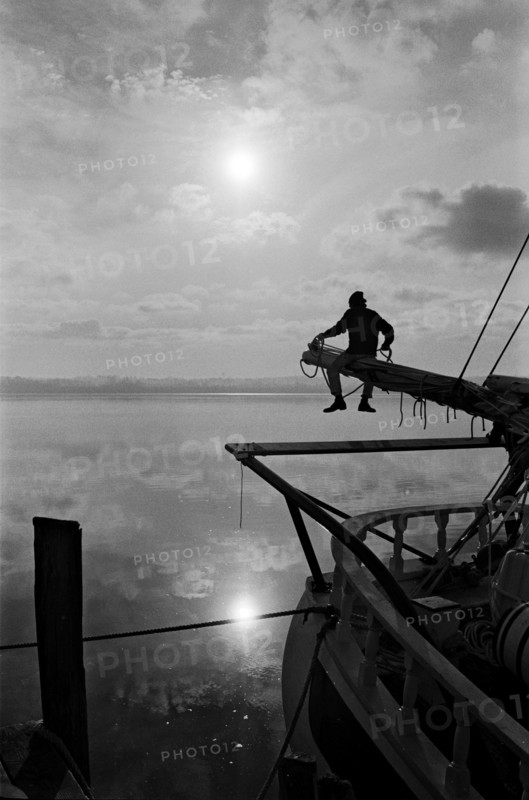 Sailor Sitting on Pole on Sailboat