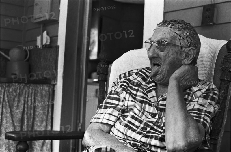 Elderly Woman Sitting on Porch and Sticking Tongue Out