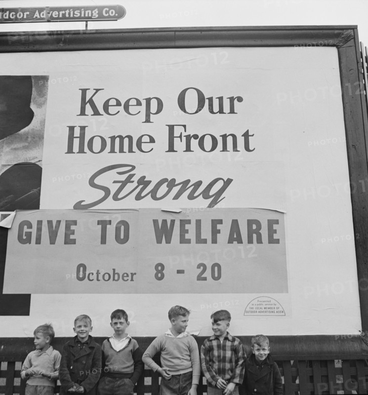 Group of Boys under Billboard, their Fathers work in nearby Defense Plants, near Lititz, Pennsylvania, USA, Marjorie Collins for Office of War Information, November 1942