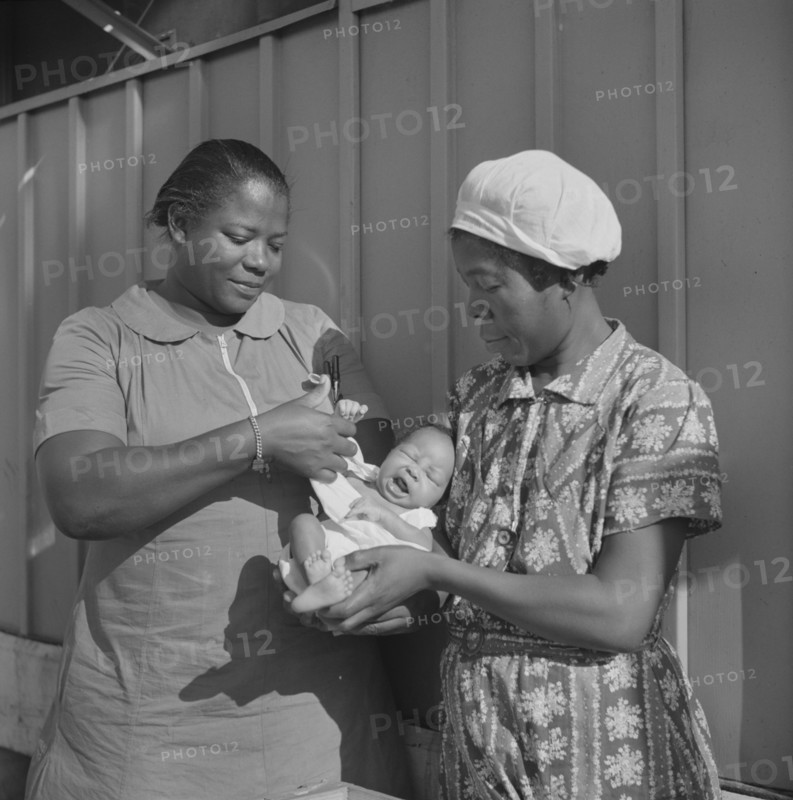 Nurse Examining Infant with Mother and Child Receiving Prenatal and Postnatal Care, Okeechobee Migratory Labor Camp, Belle Glade, Florida, USA, Marion Post Wolcott for Farm Security Administration, June 1940