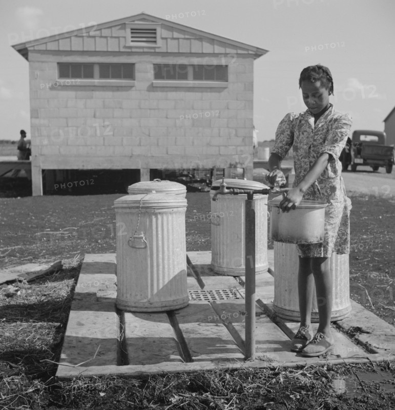 Young Girl Filling Pot with Water, Okeechobee Migratory Labor Camp, Belle Glade, Florida, USA, Marion Post Wolcott for Farm Security Administration, June 1940