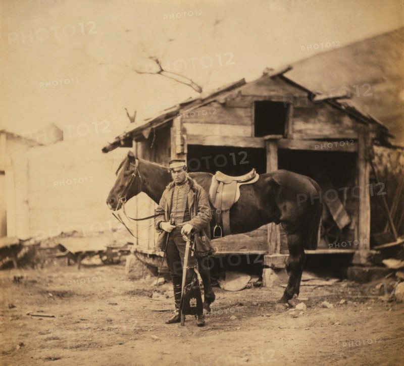 British Captain King, full-length Portrait in Uniform, Standing with Horse, Wooden Huts in Background, Crimean War, Crimea, Ukraine, by Roger Fenton, 1855