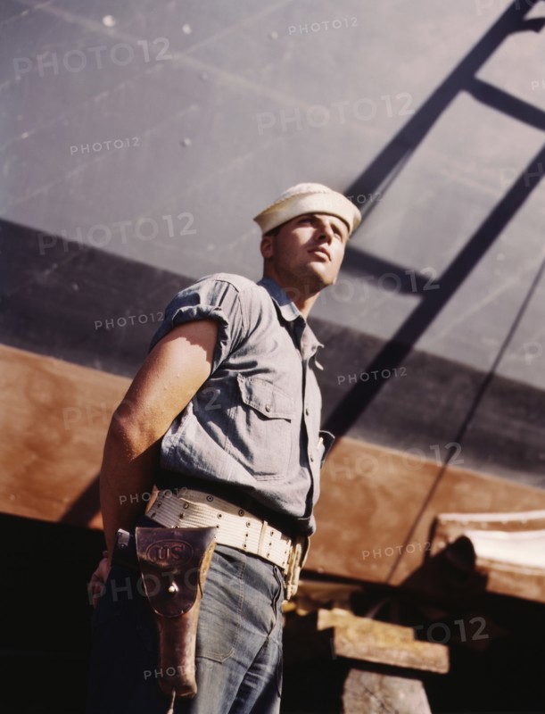 Coast Guard Sentry Standing Watch over New Torpedo Boat Under Constructions at Shipyard, Higgins Industries, Inc., New Orleans, Louisiana, USA, Howard R. Hollem for Office of War Information, July 1942