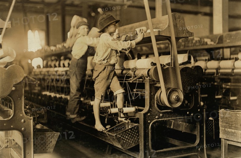 Two Young Boys Climbing on Spinning Frame to Mend Broken Threads and Put Back Empty Bobbins, Bibb Mill No. 1, Macon, Georgia, USA, Lewis Hine for National Child Labor Committee, January 1909