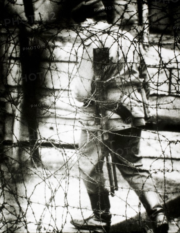 East German Border Guard Viewed Through Barbed Wire Fence, 1965