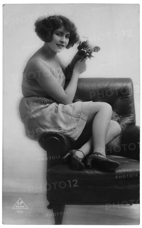 French Lingerie Model Seated on Arm of Chair Holding Flowers, circa 1920