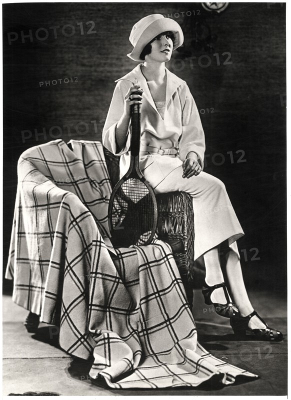 Fashionable Young Woman in White Jersey Sport Costume with Plaid Coat-Cape, Holding Tennis Racquet, Portrait, circa 1922