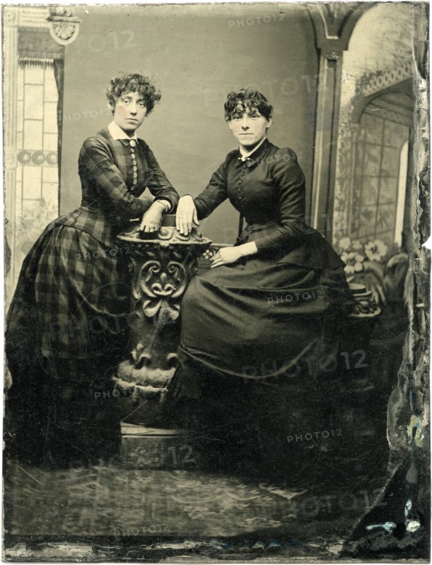 Portrait of Two Adult Women, One Seated, Both Leaning on Short Pillar, circa 1870