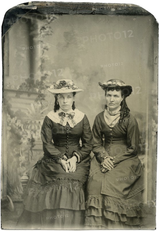 Portrait of Two Adult Women in Hats and Long Dresses, Both Seated with Hands Folded, Studio Shot, circa 1870