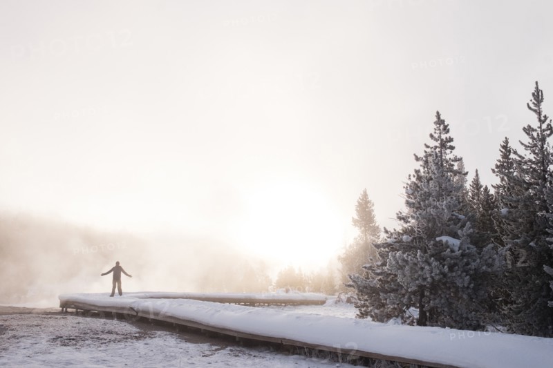 Man Raising Arms in Snowy Landscape at Sunrise