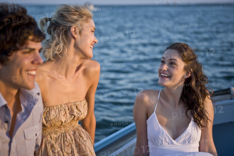 Two Young Women and Young Man Relaxing on Boat